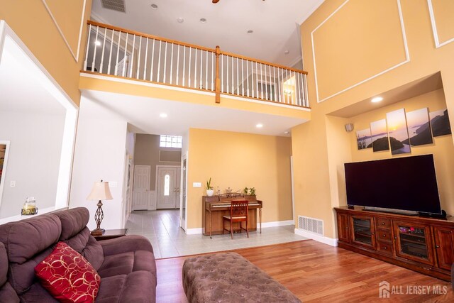 living room with a towering ceiling, wood finished floors, and baseboards