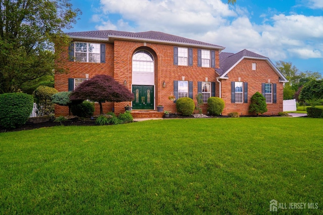 view of front of home with a front lawn, brick siding, and french doors