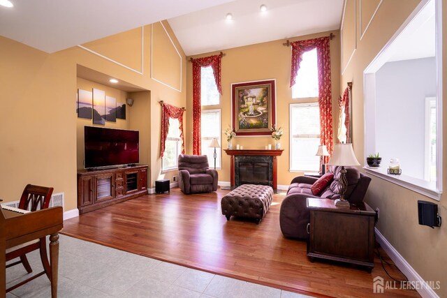 tiled living room featuring a glass covered fireplace, recessed lighting, and baseboards
