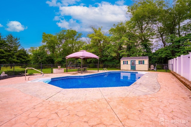 view of pool with a gazebo, a fenced backyard, a patio area, and view of wooded area