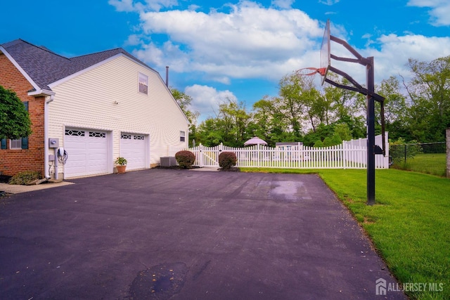 view of side of property featuring driveway, a garage, central AC, and a gate