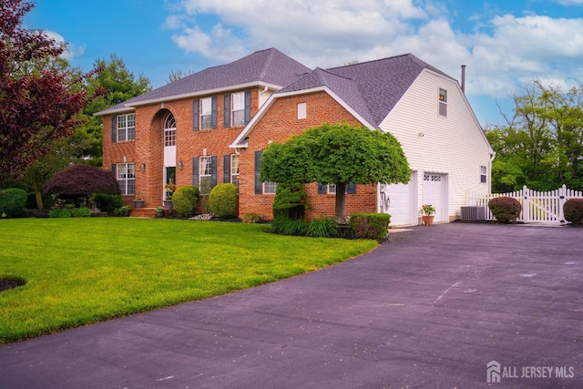 colonial home with a garage, brick siding, driveway, a gate, and central air condition unit