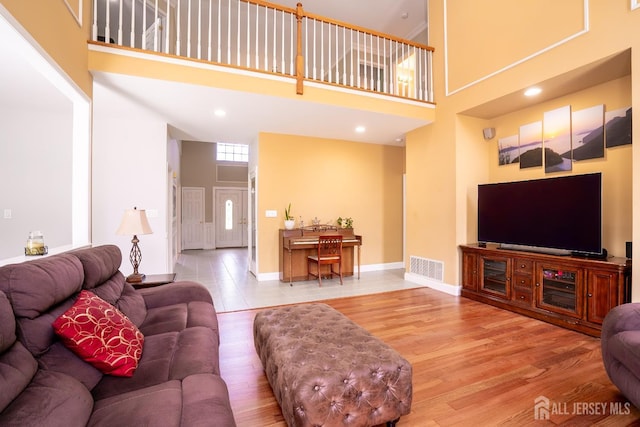living room featuring a towering ceiling, wood finished floors, and baseboards