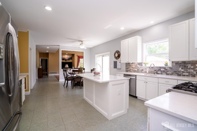 kitchen featuring stainless steel appliances, backsplash, a center island, light countertops, and plenty of natural light