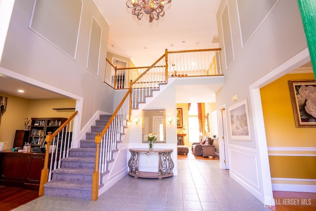 stairway featuring a towering ceiling, a chandelier, tile patterned flooring, and baseboards