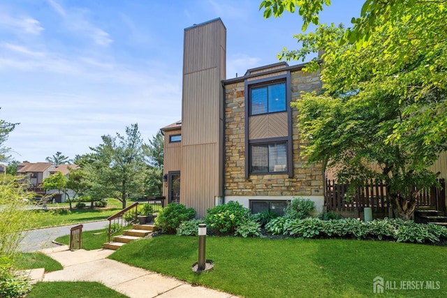view of property exterior featuring stone siding, a yard, and a chimney