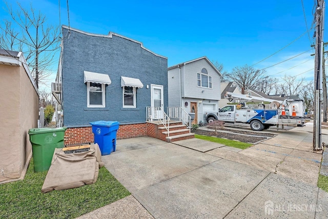 rear view of property featuring driveway and stucco siding