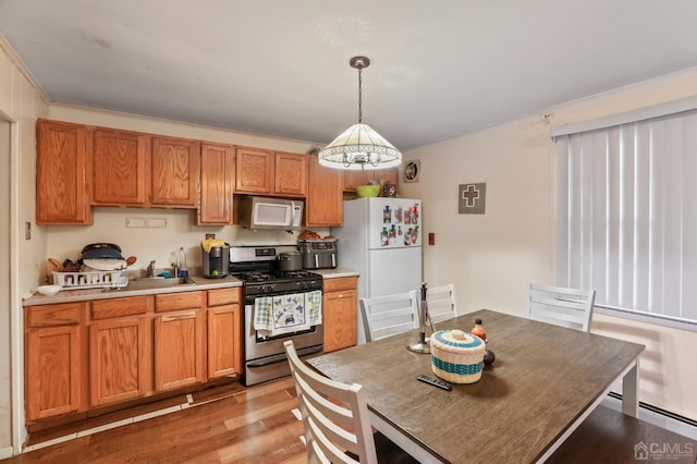 kitchen with light wood-type flooring, ornamental molding, white appliances, pendant lighting, and a chandelier