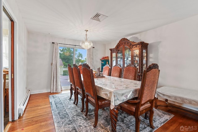 dining space featuring an inviting chandelier, light wood-type flooring, and a baseboard heating unit