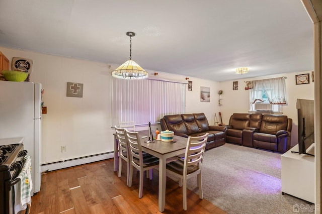 dining space featuring hardwood / wood-style flooring, an inviting chandelier, and a baseboard heating unit