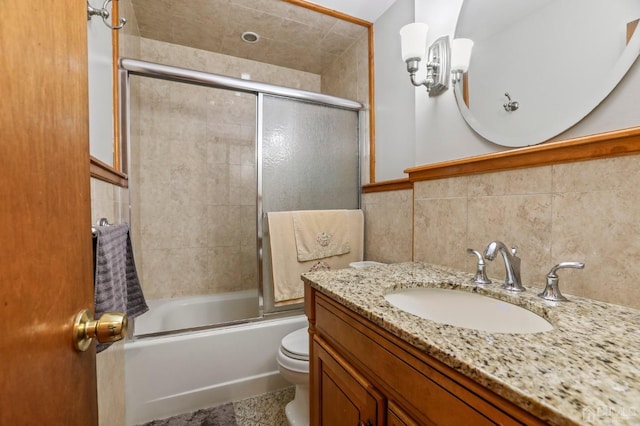 full bathroom with combined bath / shower with glass door, decorative backsplash, vanity, tile walls, and toilet