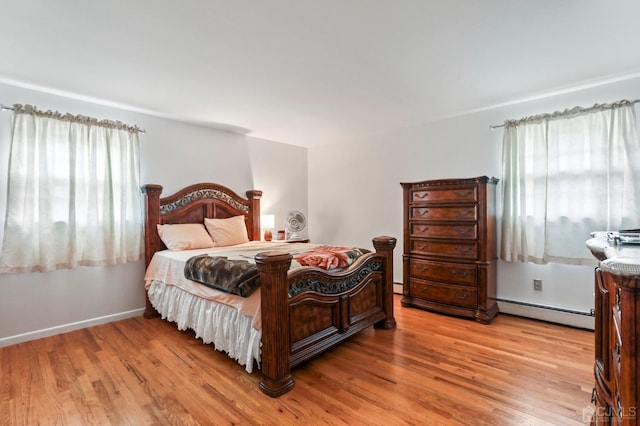 bedroom with a baseboard heating unit and light wood-type flooring