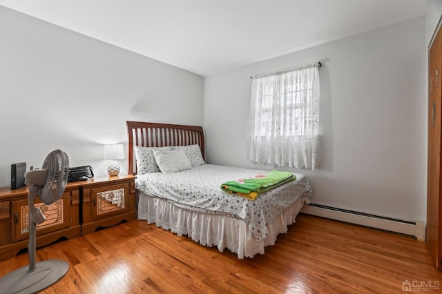 bedroom with light hardwood / wood-style floors and a baseboard heating unit