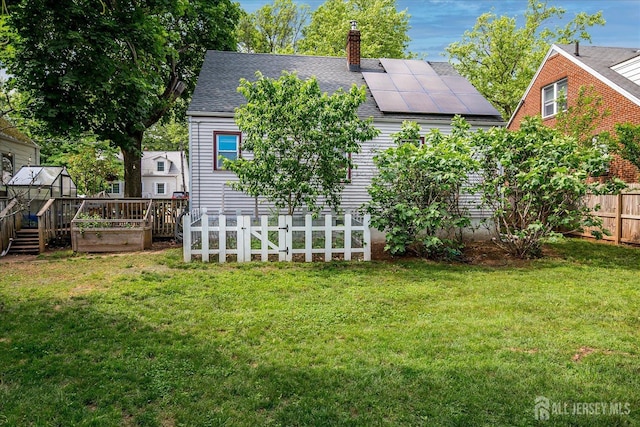 414 Graham St, Highland Park, NJ 08904 - rear view of house featuring a shingled roof, roof mounted solar panels, a chimney, and a garden