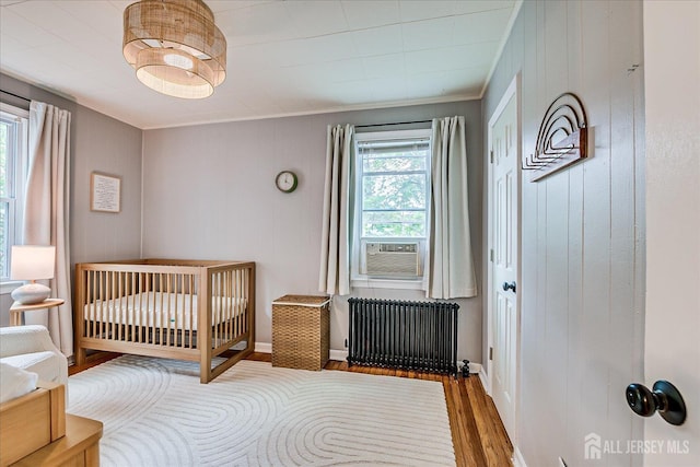 414 Graham St, Highland Park, NJ 08904 - bedroom featuring radiator heating unit, wood finished floors, cooling unit, ornamental molding, and a nursery area