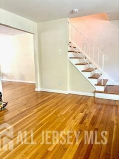 318 High St, Perth Amboy, NJ 08861 - unfurnished living room with wood finished floors and stairs