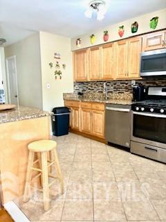 318 High St, Perth Amboy, NJ 08861 - kitchen with appliances with stainless steel finishes, backsplash, light stone countertops, and light tile patterned floors