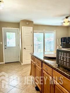 318 High St, Perth Amboy, NJ 08861 - kitchen featuring brown cabinets, light tile patterned flooring, a ceiling fan, and dark countertops