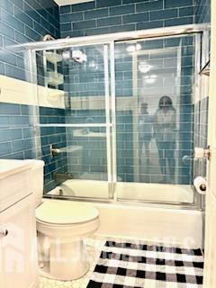 318 High St, Perth Amboy, NJ 08861 - bathroom featuring combined bath / shower with glass door, tile walls, and vanity