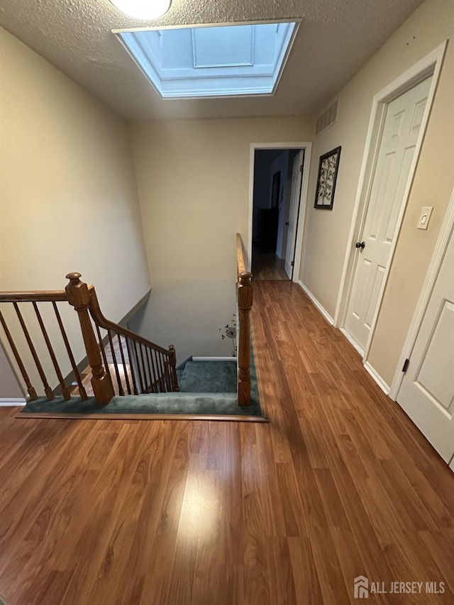 741 S Middlesex Ave S, Colonia, NJ 07067 - stairs featuring wood finished floors, a skylight, a textured ceiling, and baseboards
