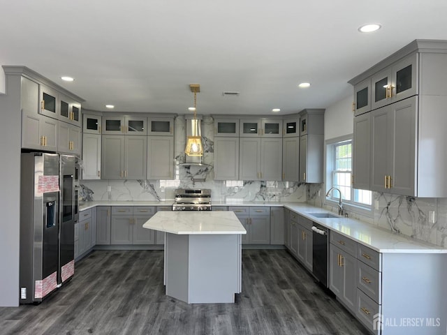 kitchen featuring gray cabinetry, wall chimney exhaust hood, a kitchen island, and stainless steel appliances