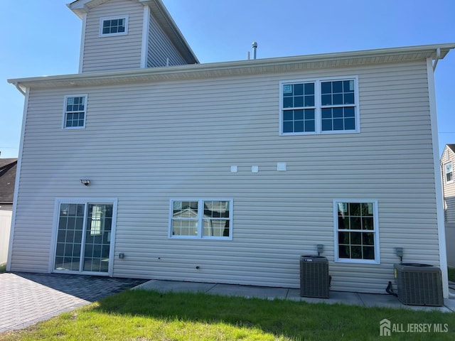 back of property with a lawn and central air condition unit