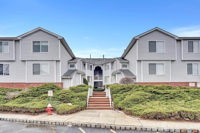 view of front of home with stairs, a residential view, and brick siding