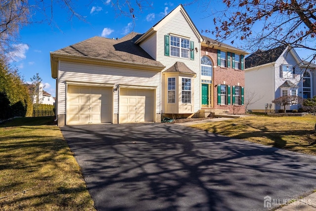 traditional-style house with a garage, driveway, and a front lawn