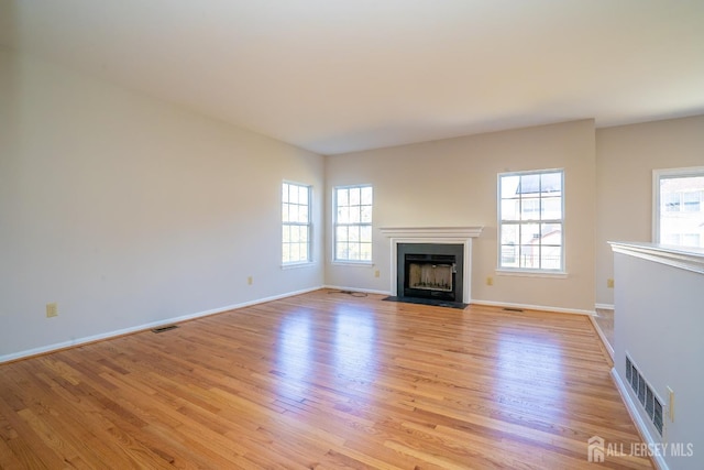 17 Larkspur Dr, South Brunswick, NJ 08810 - unfurnished living room featuring visible vents, light wood-type flooring, plenty of natural light, and a fireplace with flush hearth