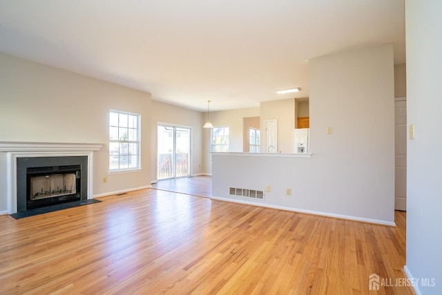 17 Larkspur Dr, South Brunswick, NJ 08810 - unfurnished living room with light wood-style flooring, a fireplace with flush hearth, baseboards, and visible vents