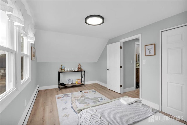 additional living space featuring baseboard heating, baseboards, lofted ceiling, and light wood finished floors