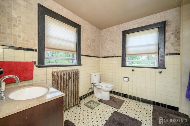 bathroom featuring radiator heating unit, tile walls, and a healthy amount of sunlight