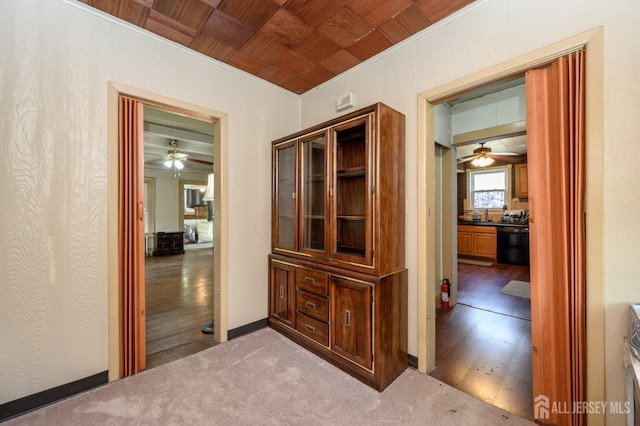 corridor featuring baseboards, ornamental molding, and wood finished floors