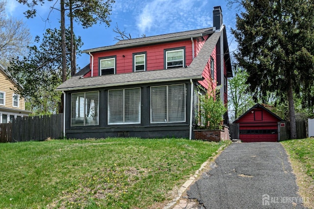 view of front of house featuring a detached garage, an outdoor structure, a chimney, and a front yard