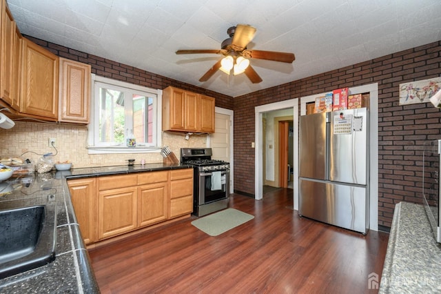 kitchen featuring dark wood-style flooring, stainless steel appliances, and brick wall