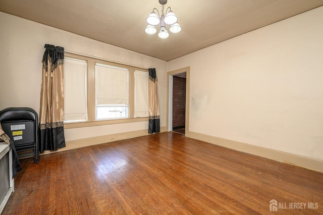 unfurnished living room with an inviting chandelier and wood finished floors