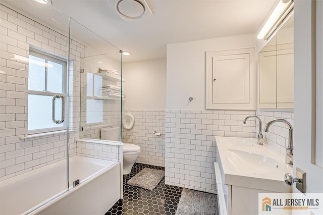 12 S 8th Ave, Highland Park, NJ 08904 - full bathroom with tile walls, toilet, bath / shower combo with glass door, tile patterned floors, and vanity