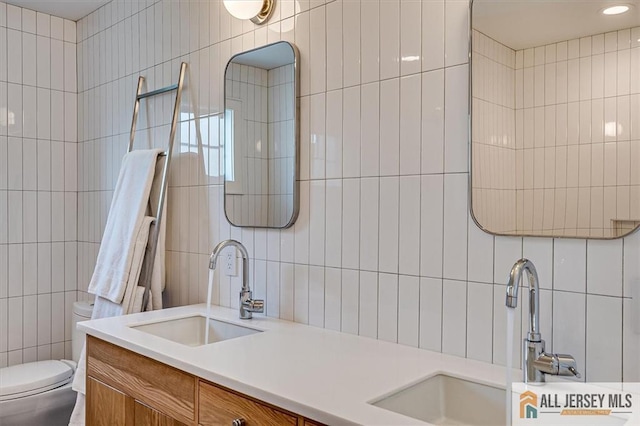12 S 8th Ave, Highland Park, NJ 08904 - bathroom featuring tile walls, double vanity, toilet, and backsplash