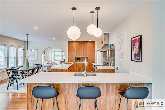 12 S 8th Ave, Highland Park, NJ 08904 - kitchen featuring wall chimney exhaust hood, a sink, brown cabinetry, modern cabinets, and gas stove