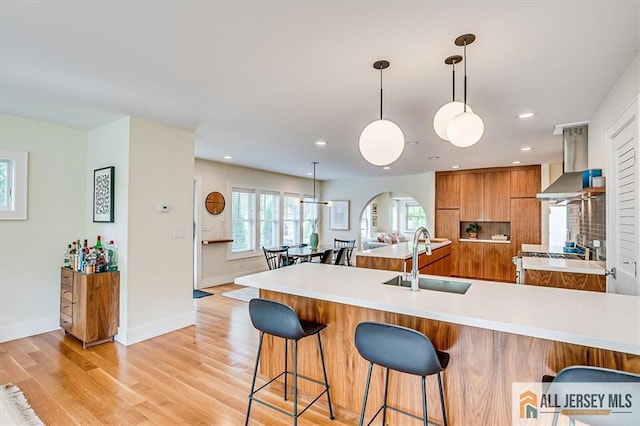 12 S 8th Ave, Highland Park, NJ 08904 - kitchen featuring a sink, modern cabinets, ventilation hood, brown cabinetry, and a kitchen bar