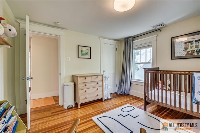 12 S 8th Ave, Highland Park, NJ 08904 - bedroom featuring light wood finished floors, baseboards, and a crib