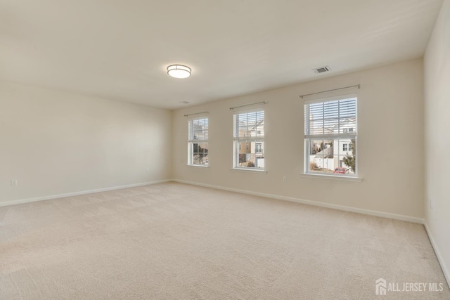 empty room featuring light carpet, visible vents, and baseboards