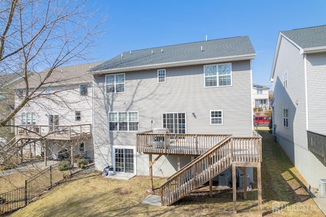 back of house with a shingled roof, a lawn, stairs, fence, and a deck