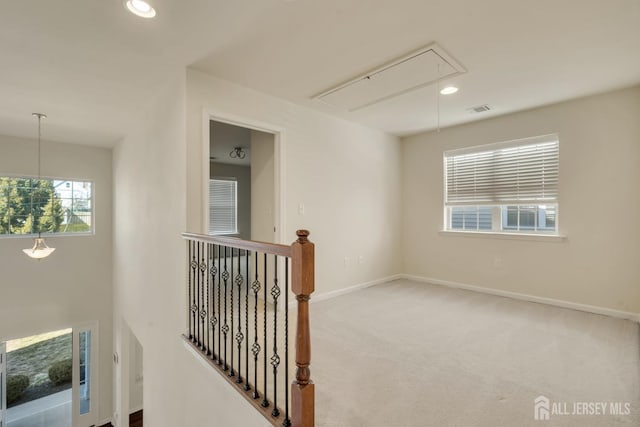 hallway featuring attic access, visible vents, baseboards, an upstairs landing, and carpet floors