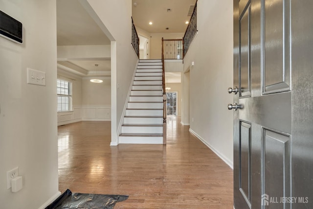 foyer entrance with a wainscoted wall, recessed lighting, a decorative wall, stairway, and wood finished floors