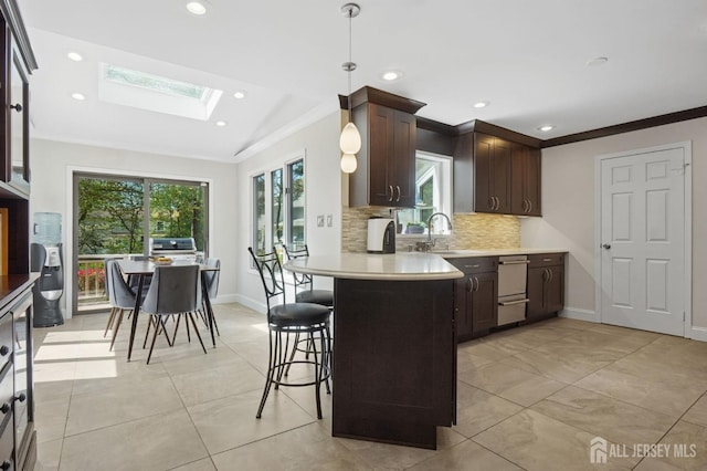 4 Franklin Ct, East Brunswick, NJ 08816 - kitchen featuring a skylight, crown molding, dark brown cabinets, light countertops, and backsplash