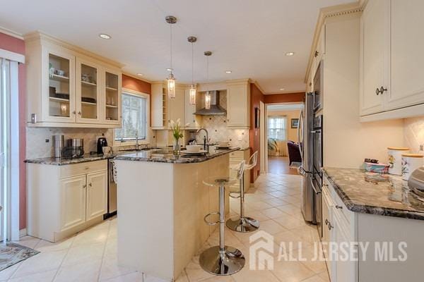 17 SE Candle Ln, East Brunswick, NJ 08816 - kitchen with a breakfast bar area, glass insert cabinets, a healthy amount of sunlight, and wall chimney exhaust hood