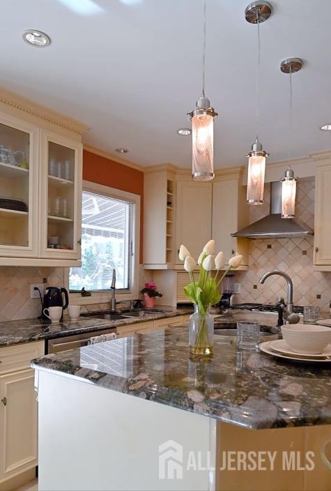 17 SE Candle Ln, East Brunswick, NJ 08816 - kitchen featuring a sink, wall chimney exhaust hood, dark stone countertops, and decorative backsplash
