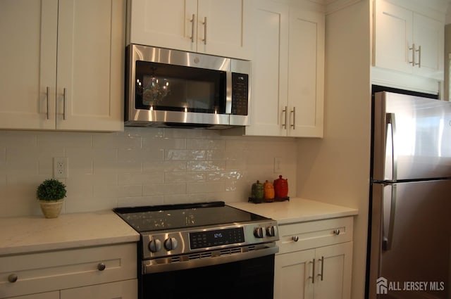 kitchen featuring backsplash, white cabinets, and stainless steel appliances