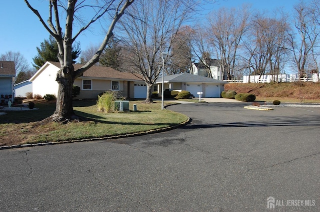 ranch-style home featuring a front yard, central AC, an attached garage, and driveway